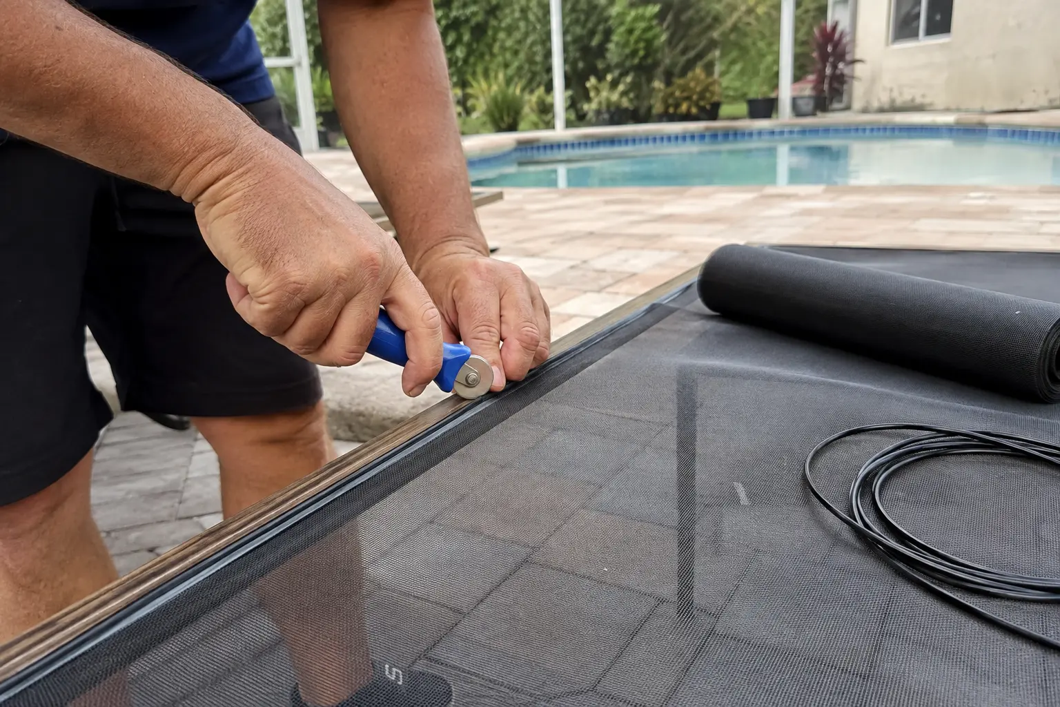 Technician replacing screen mesh in a Southwest Florida lanai